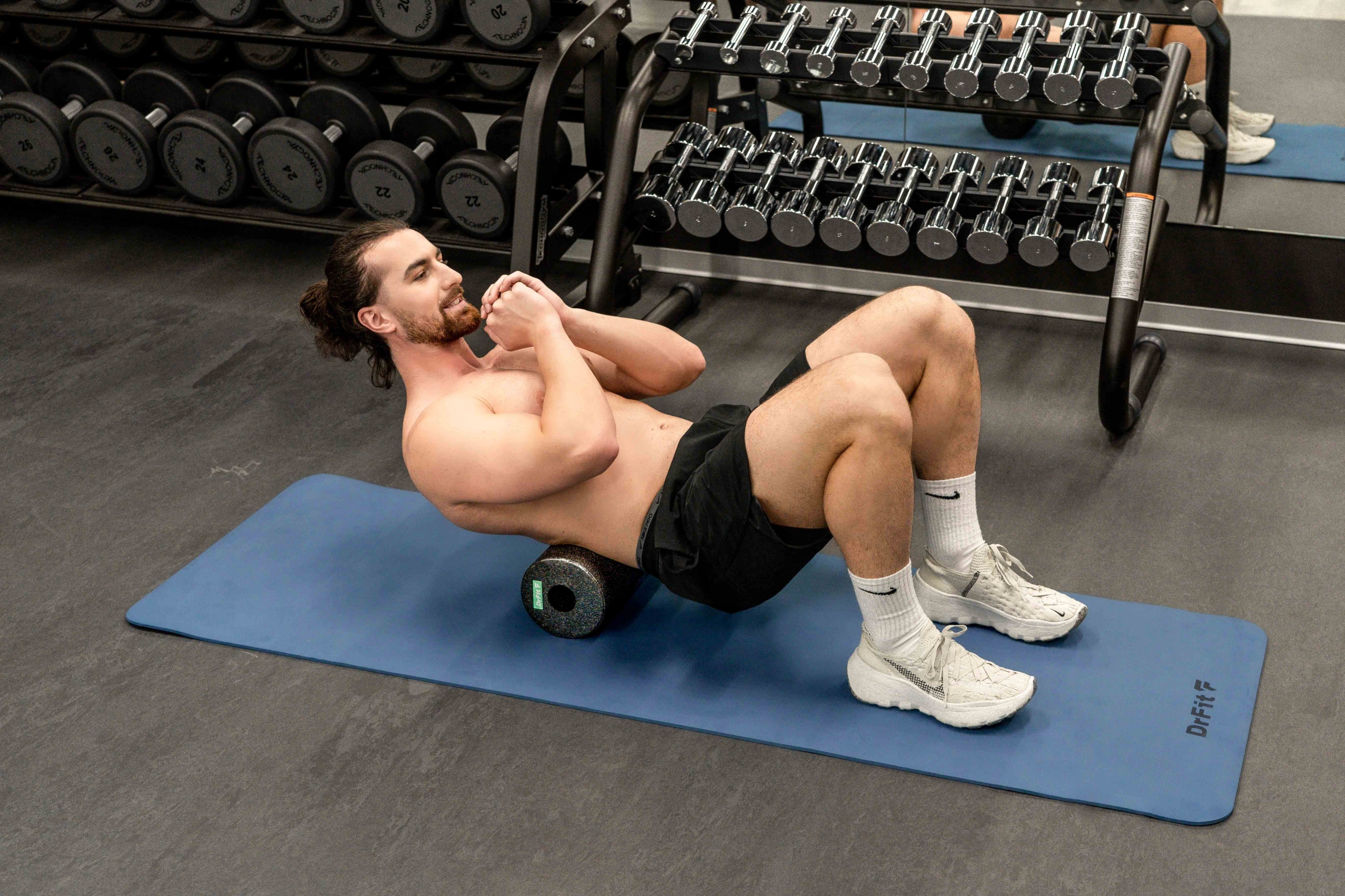 Mężczyzna wykonujący rolowanie pleców na czarnym rollerze DrFit.